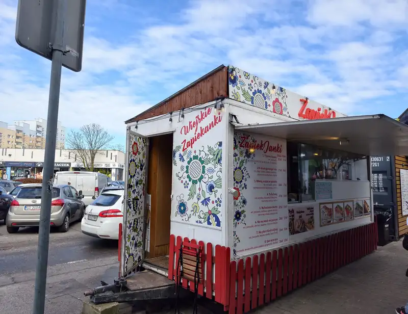Biały kiosk ZapiekJanki z kwiatowym wzorem i czerwonym płotkiem